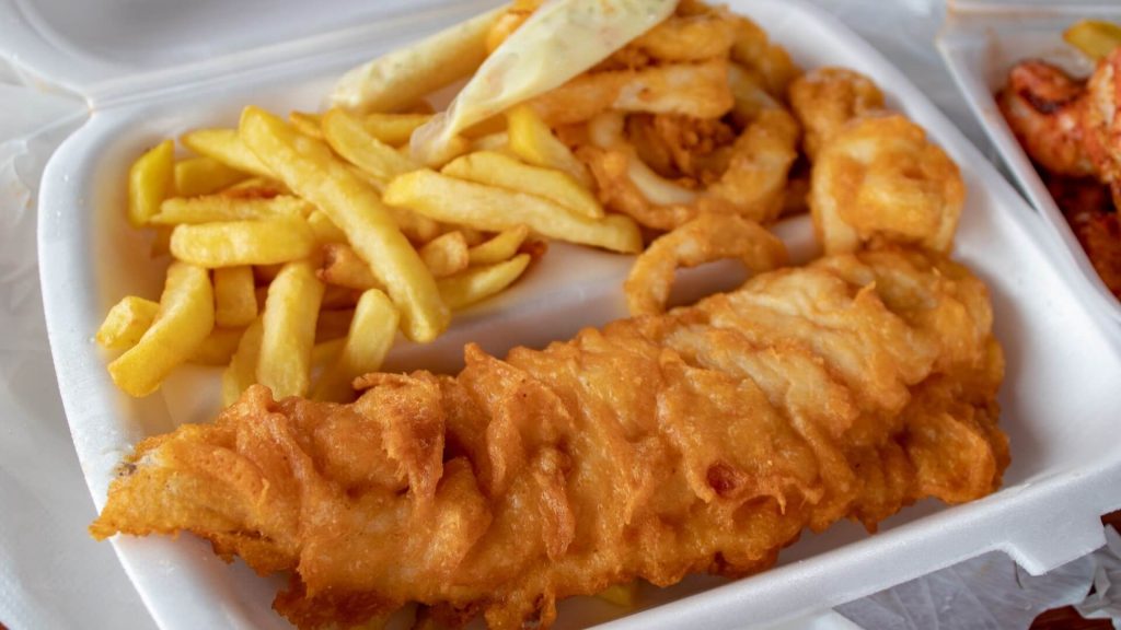 A countainer with a serving of fish and chips, a traditional street food from england and one of Europe's timeless dishes