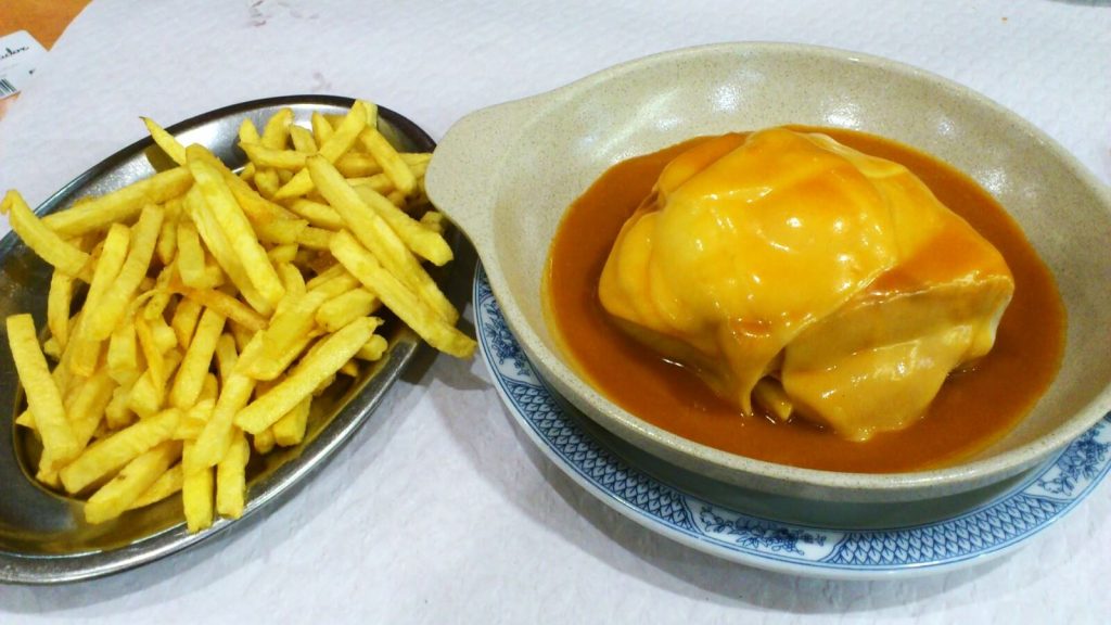 A portuguese dish called Francesinha with fries on the side, one of Europe's timeless dishes